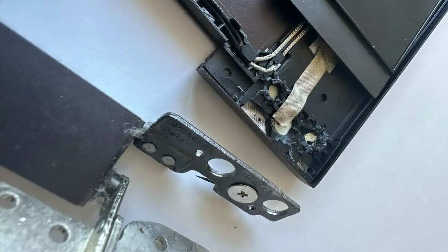 Close up of an HP Envy laptop with a broken hinge mount and loose screws