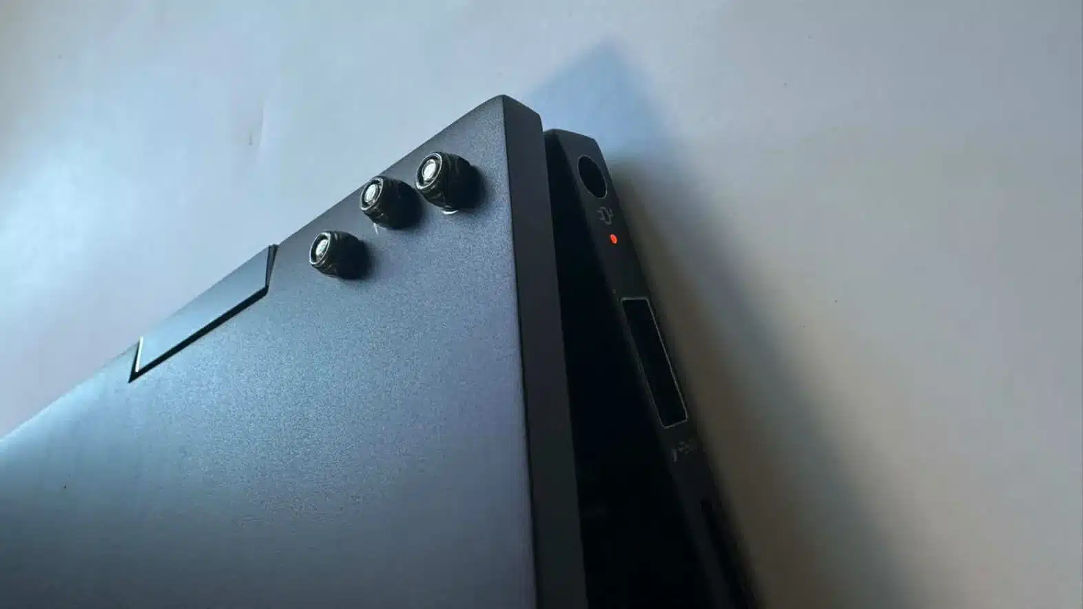 Exterior view of a laptop lid showing clean nut-and-bolt structural reinforcement for a broken hinge.