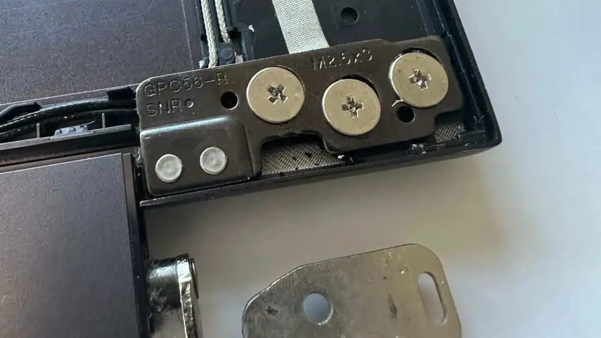 Detailed view of a structural hinge repair using reinforced metal plates and screws inside a laptop casing
