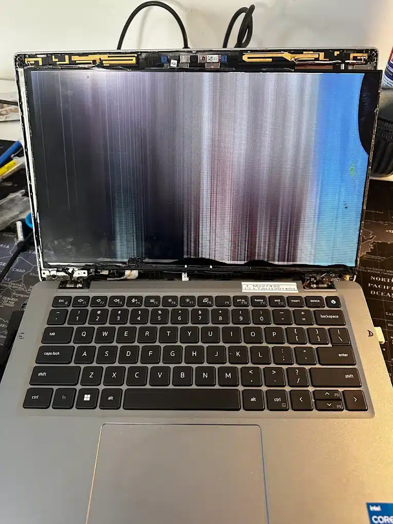 Technician carefully disconnecting internal laptop battery and display cables during a screen replacement.